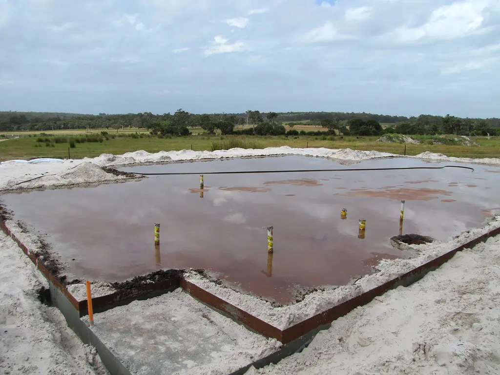 Hand pouring concrete into slab forms over gravel base and rebar