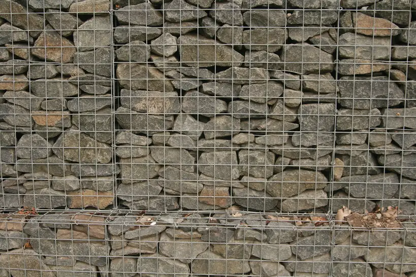 Close-up of crushed rock filling a gabion basket with visible gaps and wire mesh.