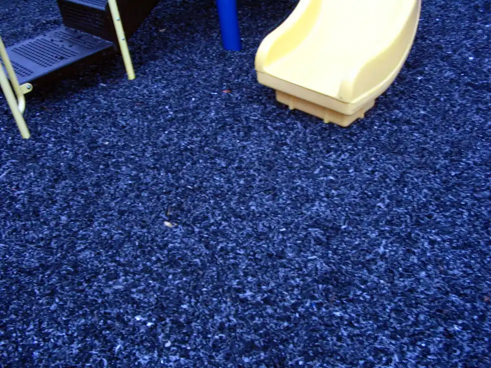 Black rubber mulch being leveled with a rake around a tree ring